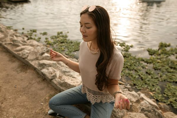 Woman meditating in a serene sunset, finding inner peace.